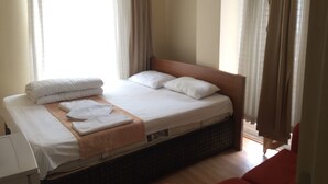 Une chambre d’hôtel avec un grand lit, une tête de lit en bois et un sol carrelé.