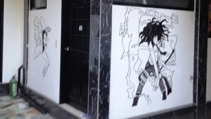 A building exterior with a black door marked '05', a wall mural, and a tiled floor. - Western Highway Lodge (Marabut)