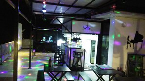 An indoor space with tables and chairs, a bar area, and a projection screen. - Western Highway Lodge (Marabut)