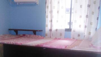 A room with a bunk bed, a small table, and an air conditioning unit on the wall.