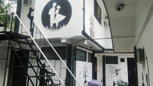 A multi-level building with a staircase, a mural of a couple, and a wall with a tree and a fairy. - Western Highway Lodge (Marabut)