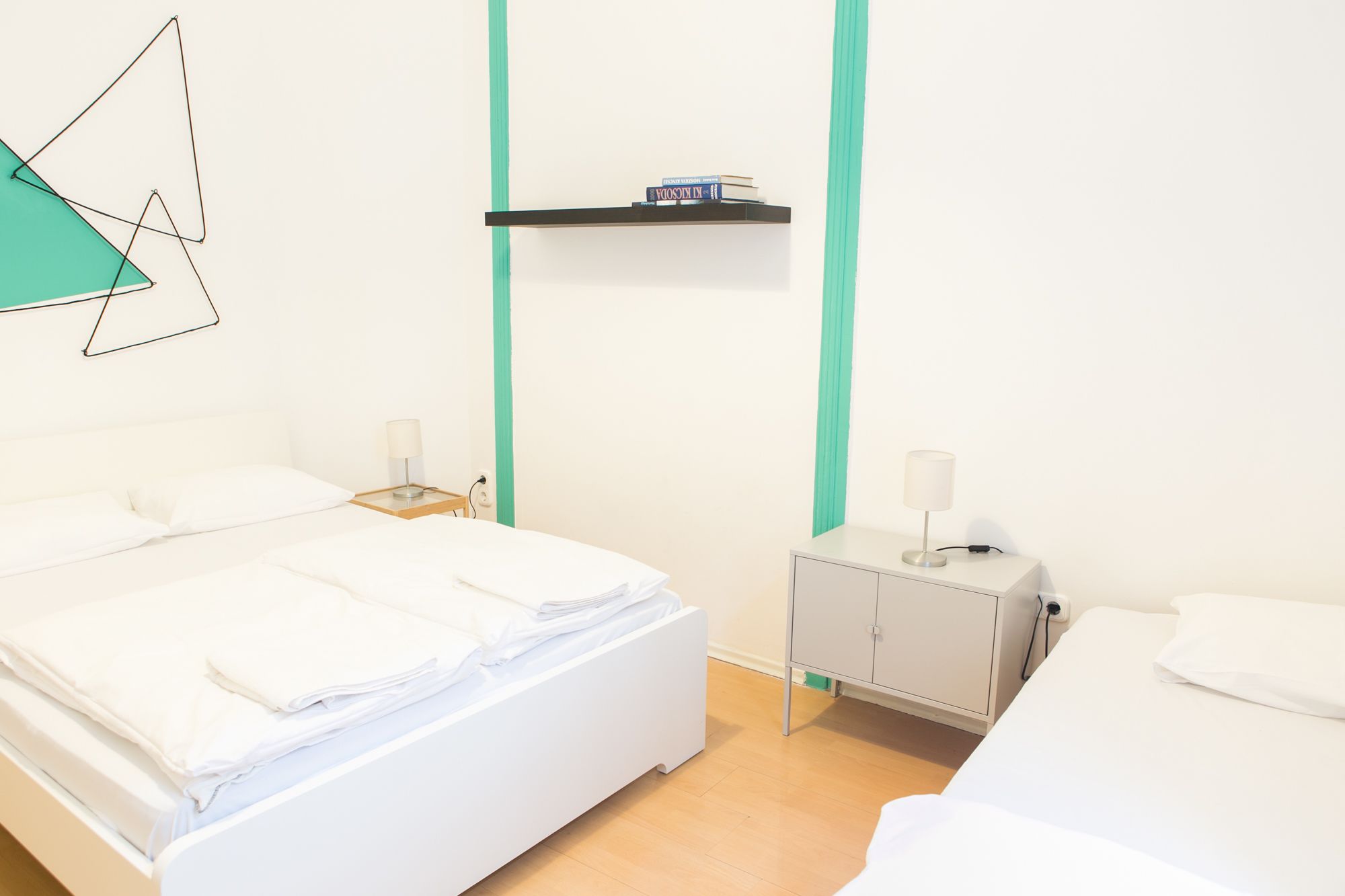 Una habitación de hotel con una cama, mesitas de noche y una estantería con libros.