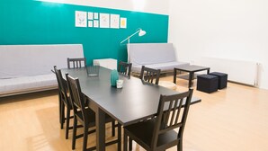 Una habitación con una mesa larga, varias sillas, un sofá, una lámpara y obras de arte en la pared.