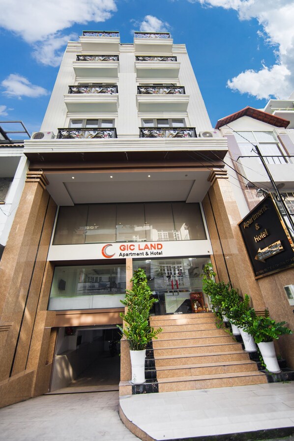 Entrada de hotel com uma placa que diz 'GIC LAND Apartment & Hotel'.