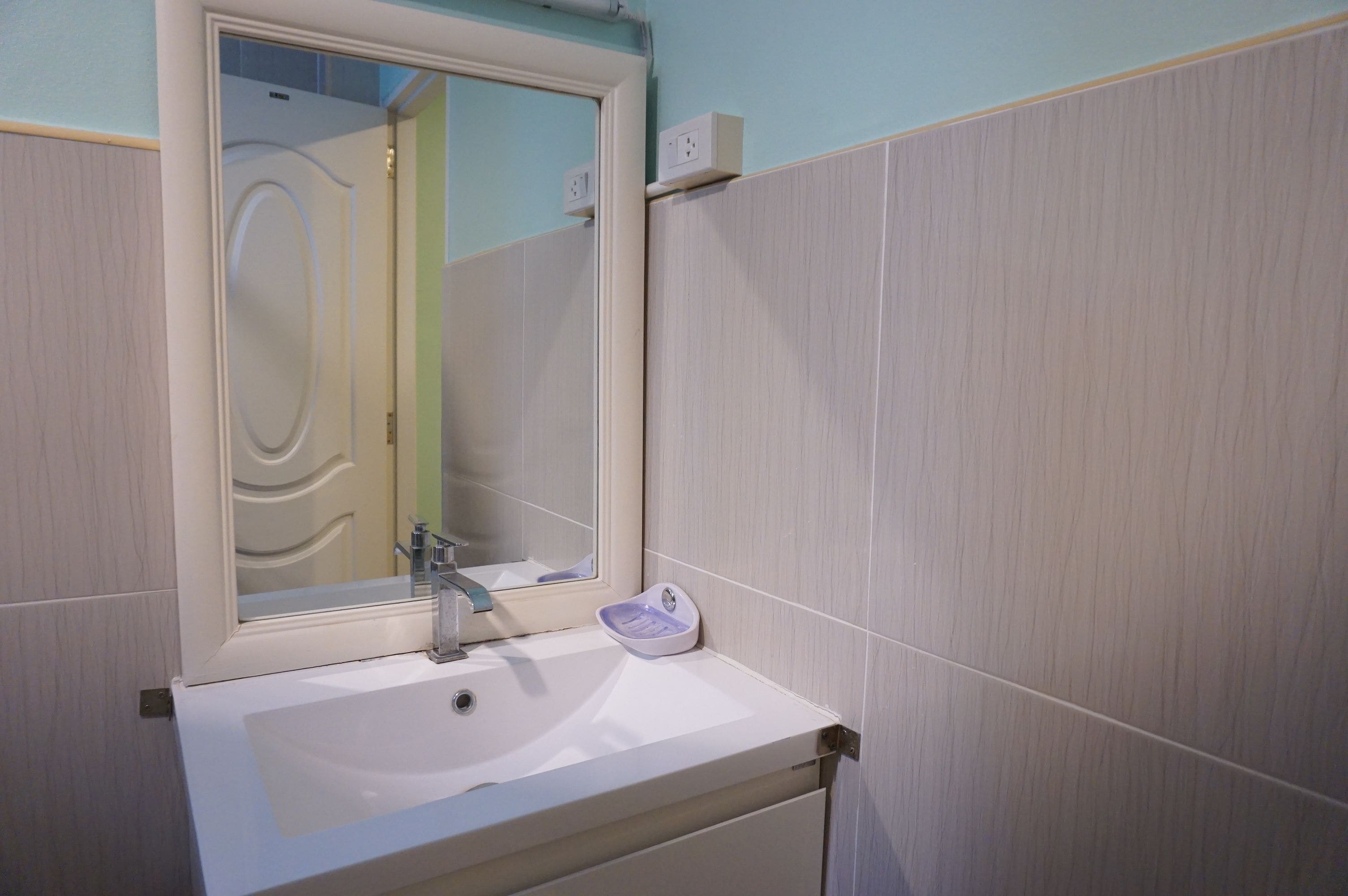 Ein Badezimmer mit einem weißen Waschbecken, einem Spiegel und einem Handtuchhalter.