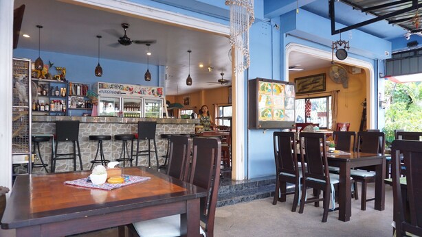 A restaurant with a bar area, multiple seating arrangements, and a decorative ceiling.