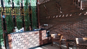 Un área de recepción con un mostrador estampado, sillas de madera y una pared de ladrillo.