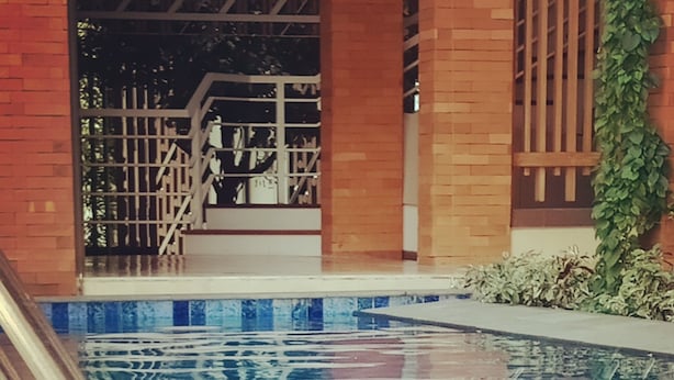 Una mesa junto a la piscina con una bebida, aperitivos y un teléfono.