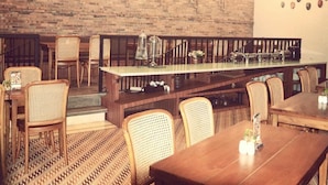 Un restaurante con mesas y sillas de madera, lámparas colgantes y una pared de ladrillo.