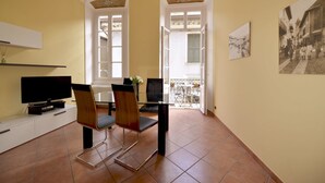 Una habitación con televisión, dos sillas, una mesa y un balcón con vistas.