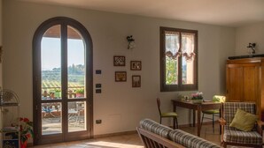 Una habitació amb un gran arc que dona a un balcó, una zona de menjador amb taula i cadires, i un sofà.