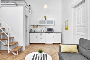 A modern kitchen with white cabinets, a microwave, and a hanging pot rack. - Legendary Ernesto II (Budapest)
