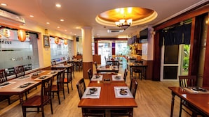 Un restaurant avec des tables et des chaises en bois, un luminaire au plafond et une vue sur la rue.