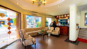 Un hall d’hôtel comprenant un comptoir d’accueil, des canapés, des fauteuils et un lustre.