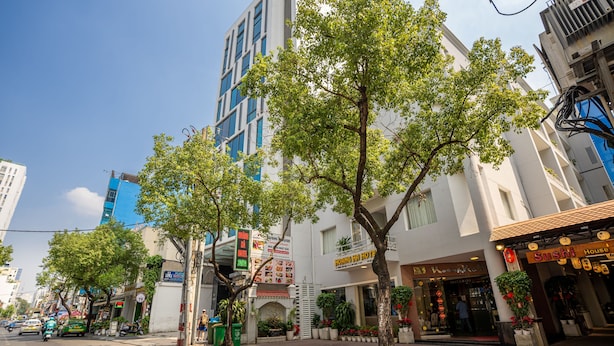 Un bâtiment moderne avec un restaurant au rez-de-chaussée, une entrée bien visible et un arbre devant.