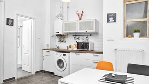 Uma cozinha compacta com máquina de lavar, micro-ondas e espaço para café.