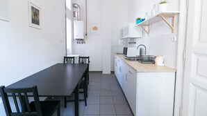 Une cuisine compacte comprenant une table et des chaises, un four à micro-ondes, un évier et un chauffe-eau.
