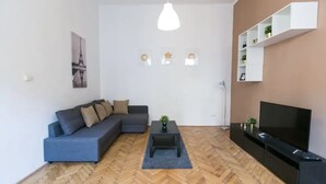Un salon moderne avec un canapé, une table basse, un téléviseur et un parquet à motifs en chevrons.