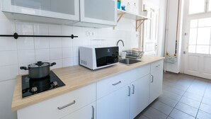 Une cuisine moderne avec des armoires blanches, un four à micro-ondes, une cuisinière et un évier.