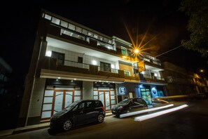 Un hotel moderno de dos plantas, con varios balcones y una entrada visible con un letrero.