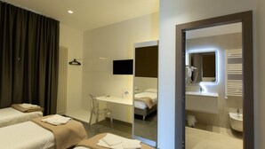 A hotel room with two beds, a desk, a chair, a mirror, and a bathroom with a sink and shower. - Hotel New Bari (Bitritto)