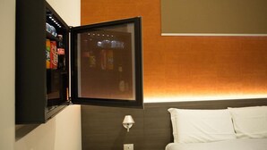 A hotel room with a bed, a wall-mounted TV, and a shelf with beverages. - Hotel New Bari (Bitritto)