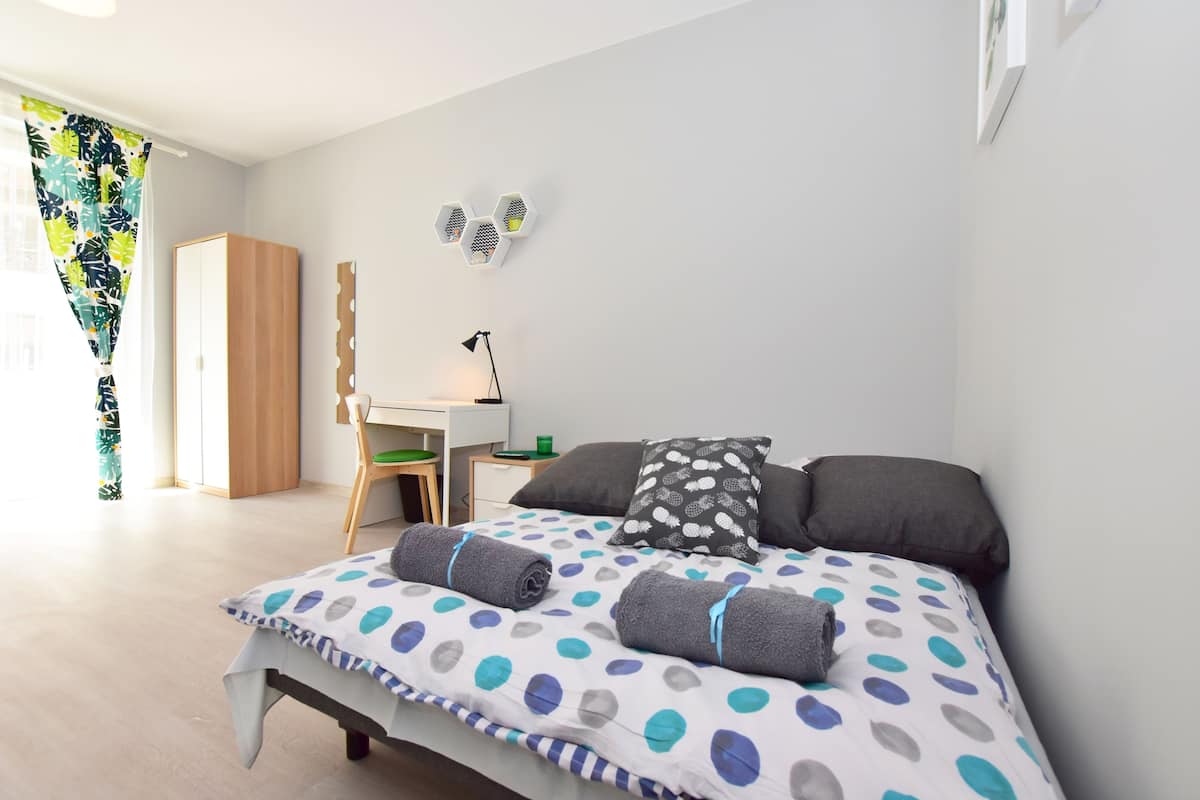 A bedroom with a bed, a desk, and a chair.