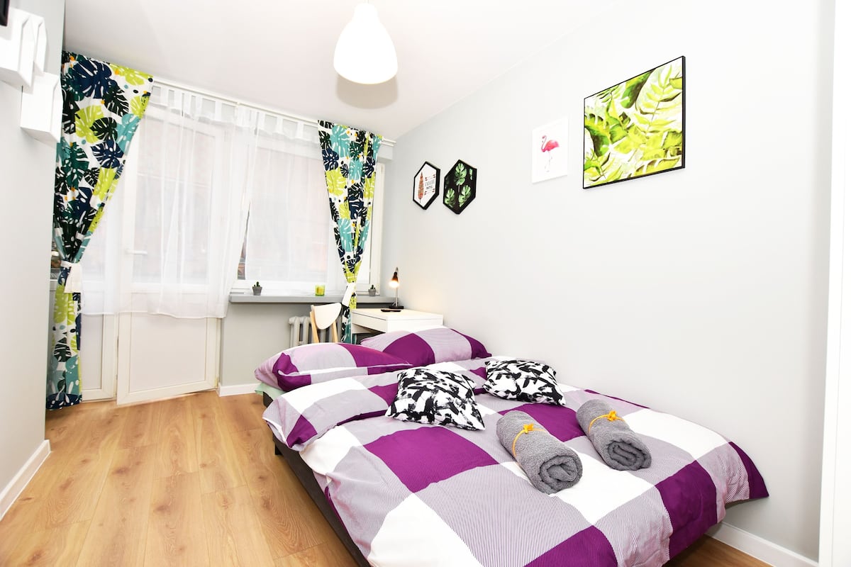 A bedroom with a bed, curtains, a desk, and a chair.