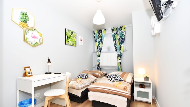 Un dormitorio moderno con escritorio, dos camas, una silla y una mesita de noche.