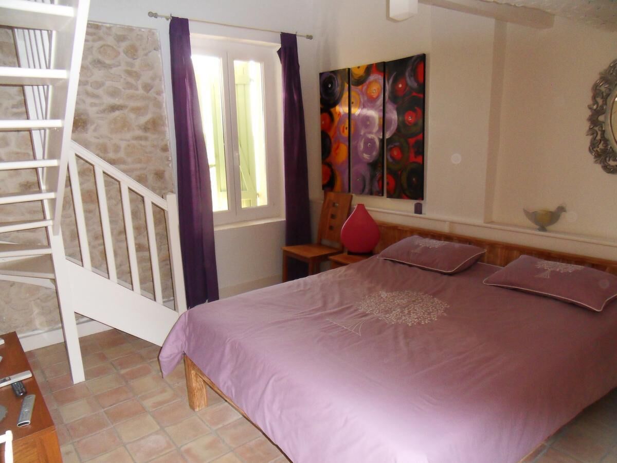 Un dormitorio con una cama, una escalera, un cuadro y una ventana.