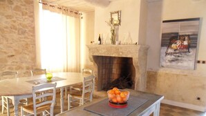 A dining area with a stone wall, a fireplace, and a painting on the wall. - Chambres d'hôtes Domaine l'Olibaou (Venelles)