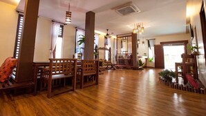 A spacious room with wooden flooring, a large wooden bench, a dining table, and a hanging light fixture. - House Of My Eternal Love - Kulai Homestay (Kulai)