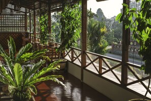 A covered balcony with potted plants, wooden railings, and a view of the street. - House Of My Eternal Love - Kulai Homestay (Kulai)