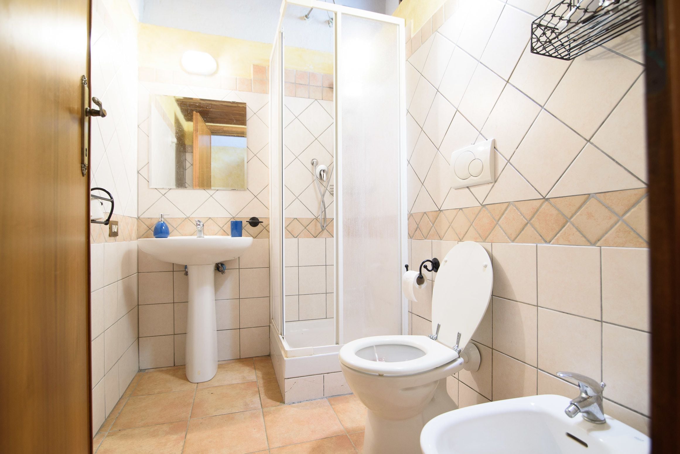 A bathroom with a shower, toilet, sink, and a mirror.