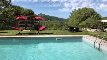 Una piscina al aire libre, sillones reclinables de piscina