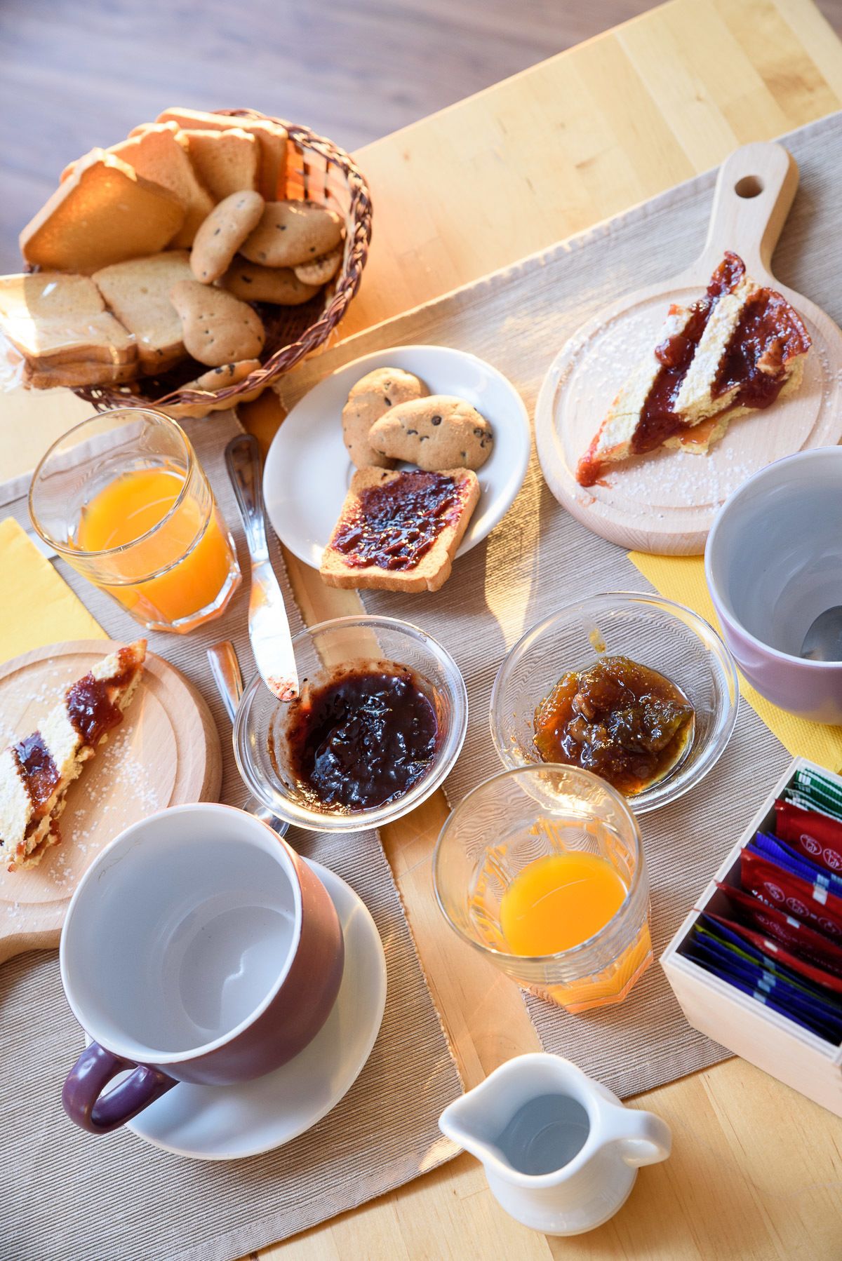 A breakfast table with various food items, including toast, biscuits, jam, and orange juice.
