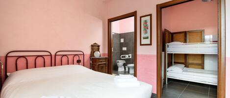 A hotel room with a large bed, a smaller bed, a wooden dresser, a mirror, and a bathroom visible through an open door.