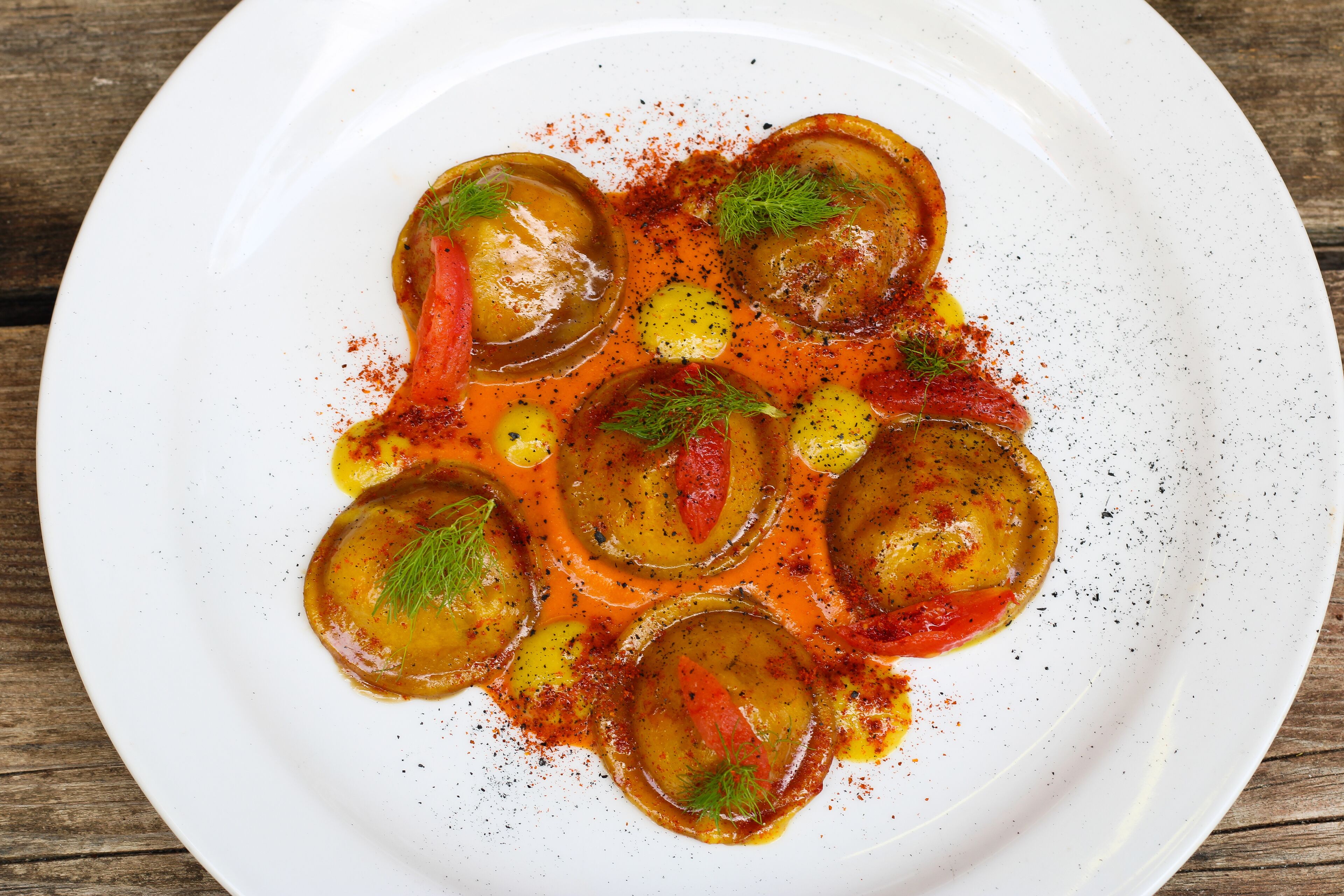 A white plate with a dish of stuffed vegetables, garnished with herbs and spices.