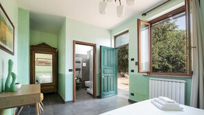 Un dormitorio con cama, escritorio y baño a la vista a través de una puerta abierta.