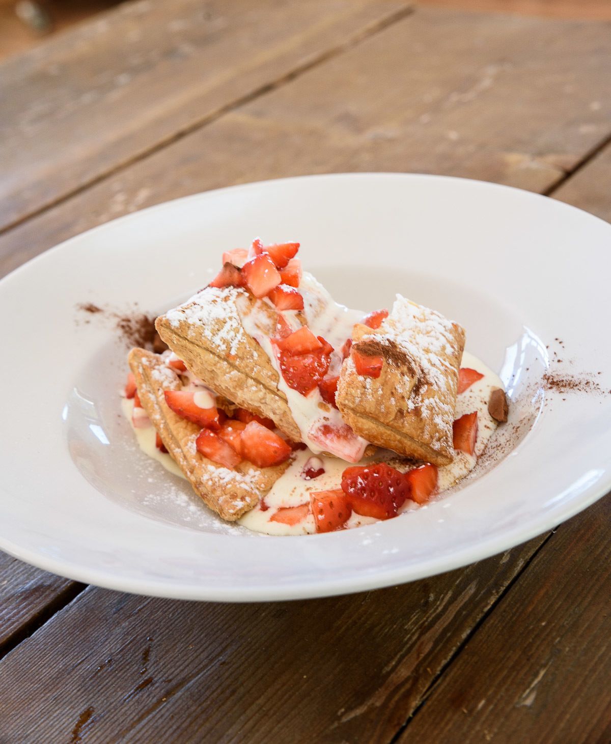 A plate of crepes topped with strawberries and powdered sugar.
