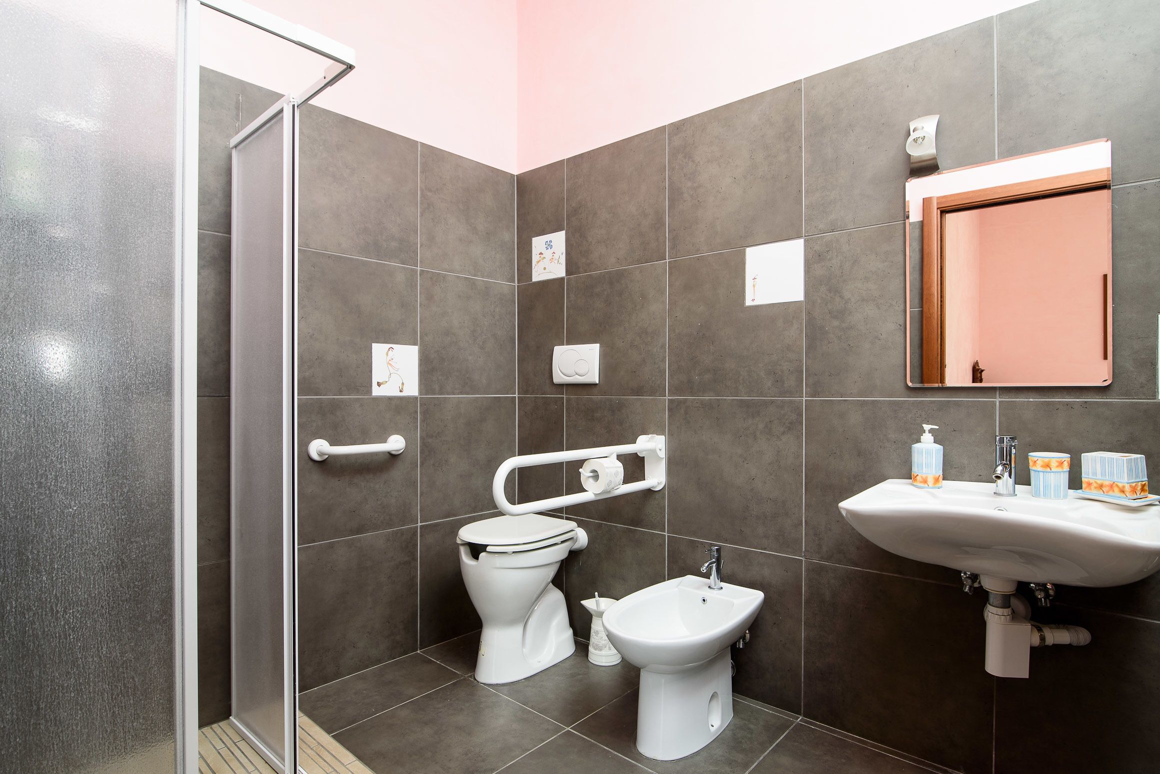 A modern bathroom with a shower, toilet, bidet, and sink.
