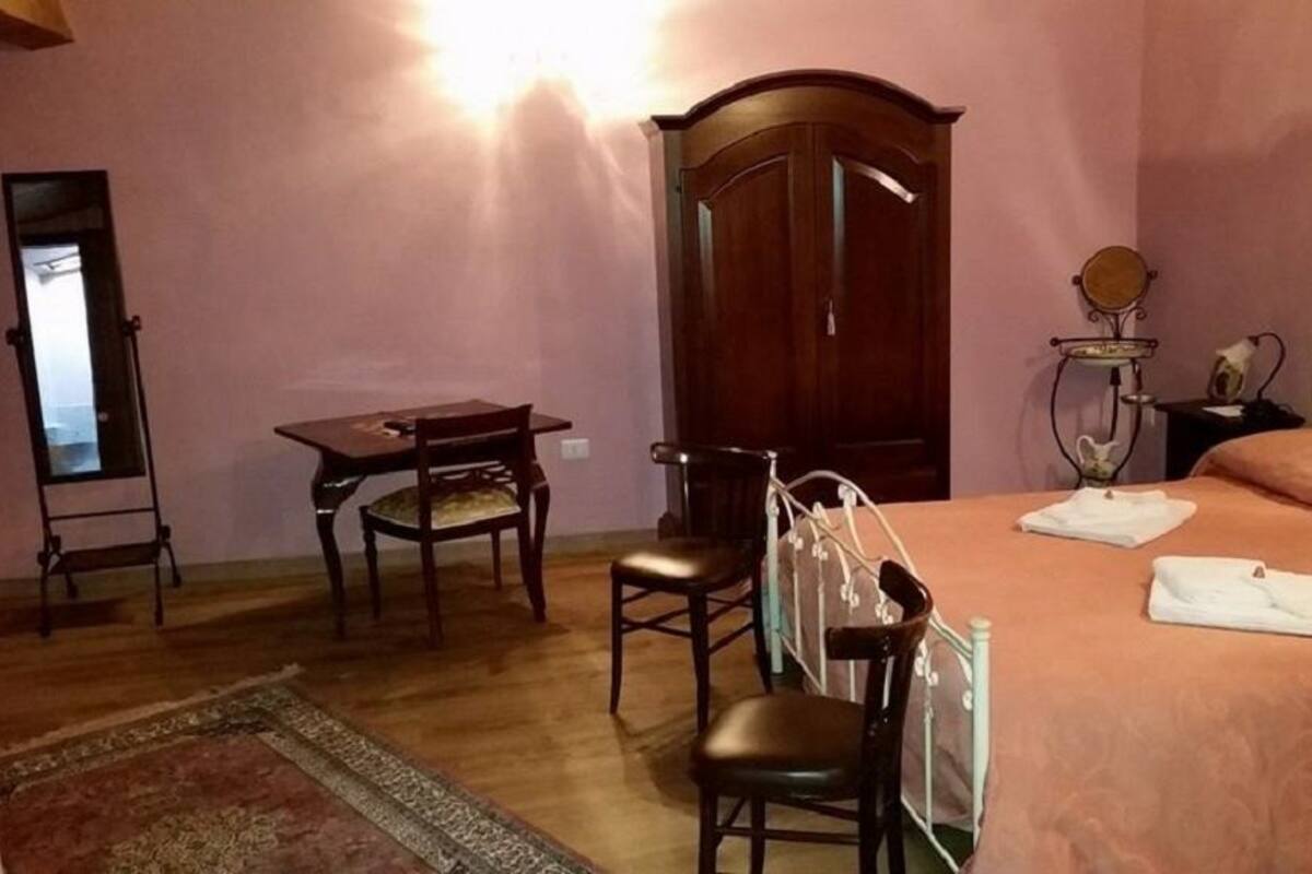 A bedroom with a bed, a desk, a chair, a wardrobe, and a mirror.