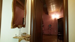 A hallway with a large mirror, a small table with a vase, and a chair. - Bed & Breakfast Dhafna Civita (Civita)