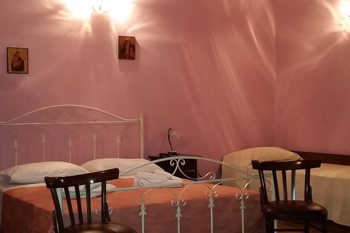 A bedroom with a bed, two chairs, a nightstand, and a bedside table.