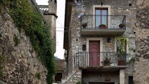 A narrow stone-paved alleyway flanked by stone buildings with balconies, leading to a door with a sign. - Bed & Breakfast Dhafna Civita (Civita)