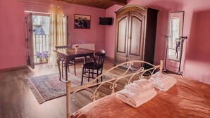 A bedroom with a bed, a wooden table with chairs, a wardrobe, and a TV. - Bed & Breakfast Dhafna Civita (Civita)