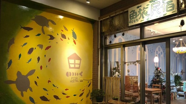 A hostel with a mural of fish and a turtle, wooden furniture, and a Christmas tree inside. - Fish hostel (New Taipei City)