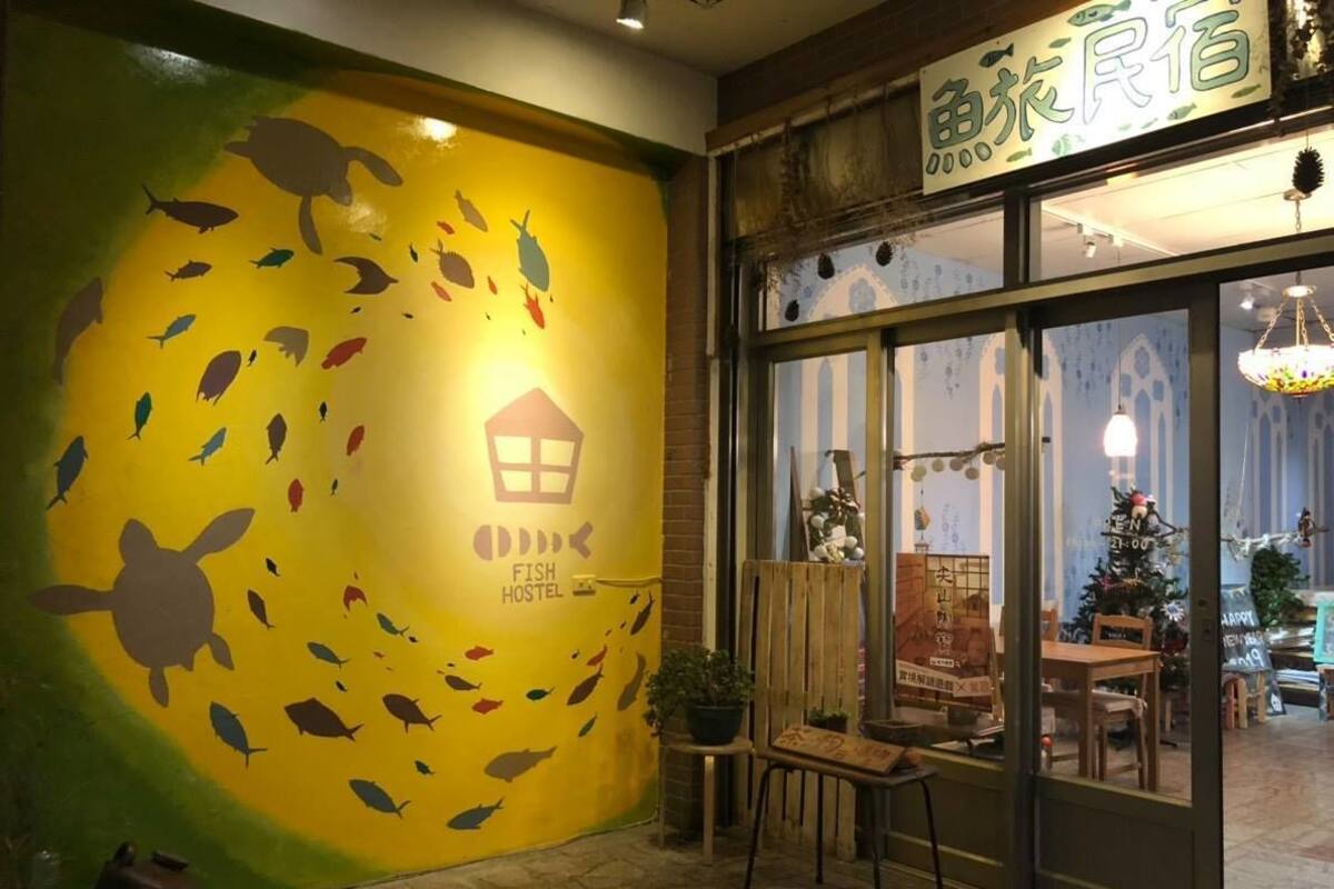 A hostel with a mural of fish and a turtle, wooden furniture, and a Christmas tree inside.