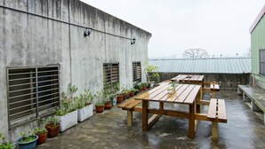A rooftop patio with wooden tables and potted plants. - Fish hostel (New Taipei City)