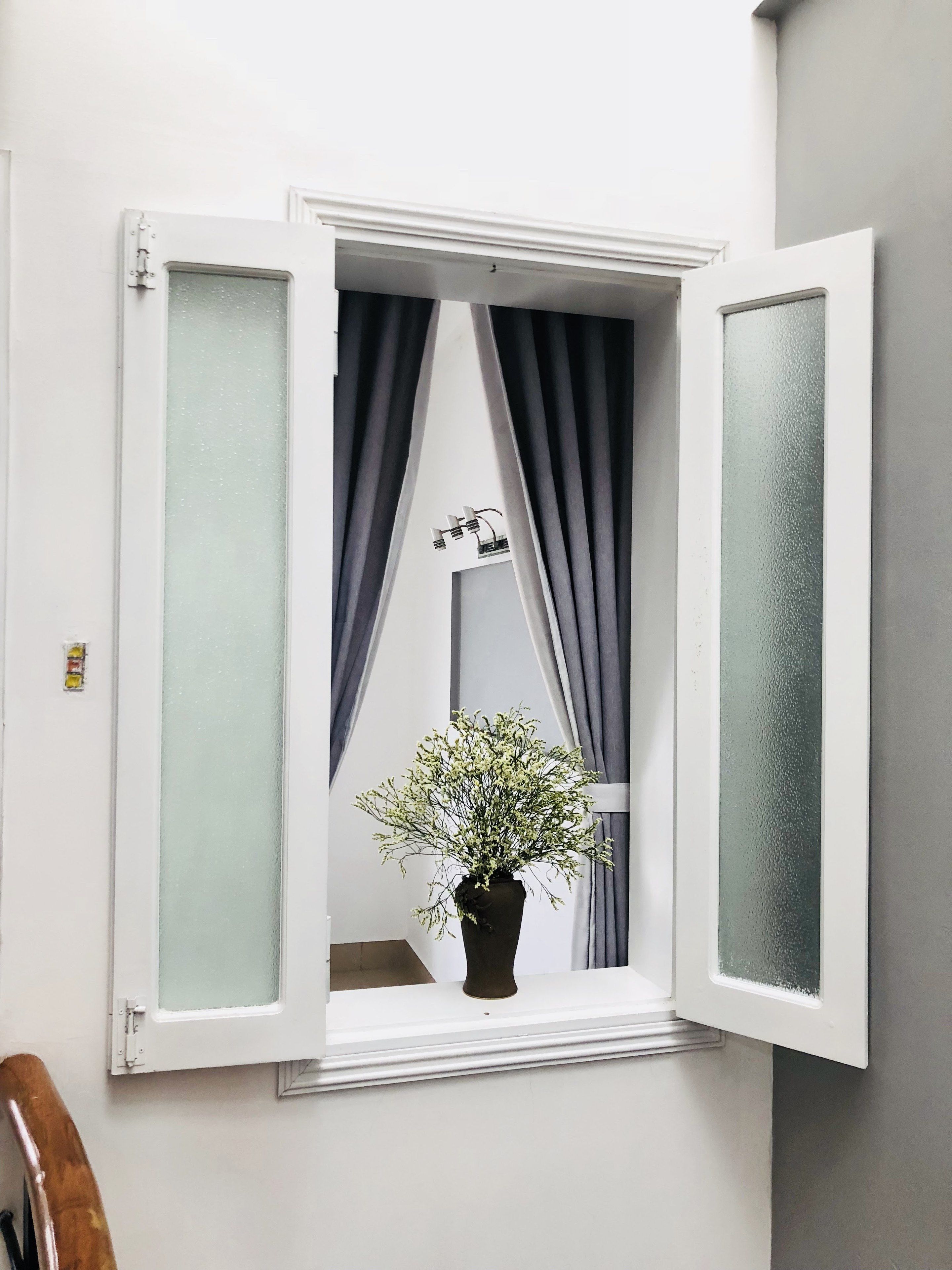 A window with frosted glass panes, a potted plant, and grey curtains.